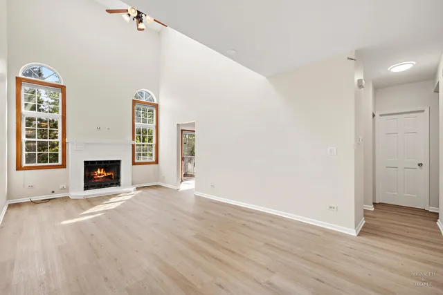 a view of an empty room with wooden floor fireplace and a window