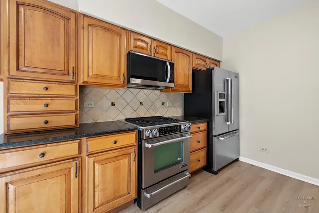 a kitchen with stainless steel appliances granite countertop white cabinets and a stove top oven