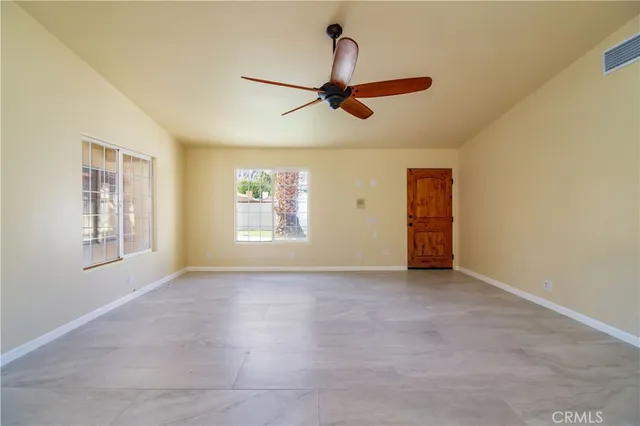 an empty room with windows and a ceiling fan