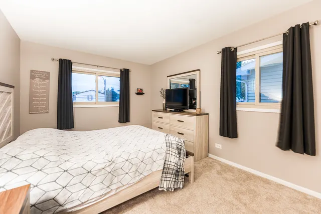 a bedroom with a bed and a flat tv screen on a dresser