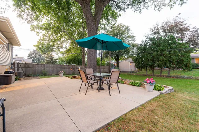 a view of backyard with table and chairs under an umbrella