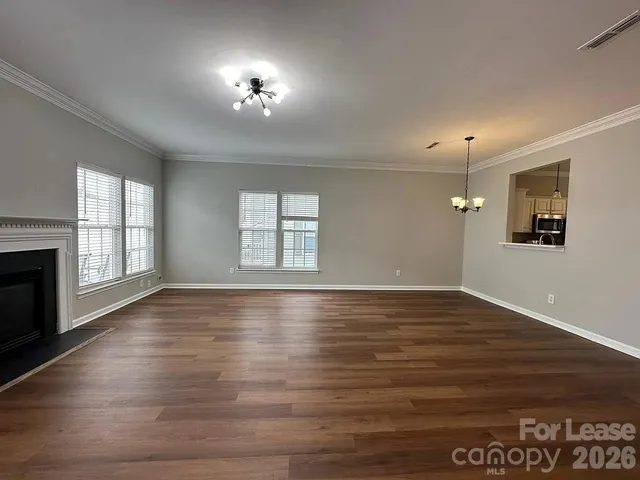 an empty room with wooden floor chandelier and windows
