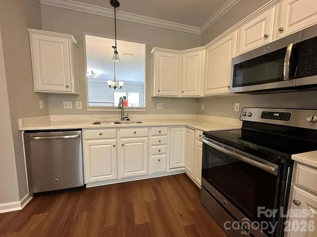 a kitchen with stainless steel appliances a stove a sink and white cabinets
