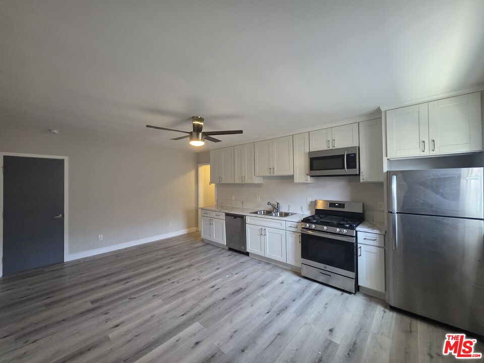 a kitchen with granite countertop a refrigerator a stove a microwave and wooden floor