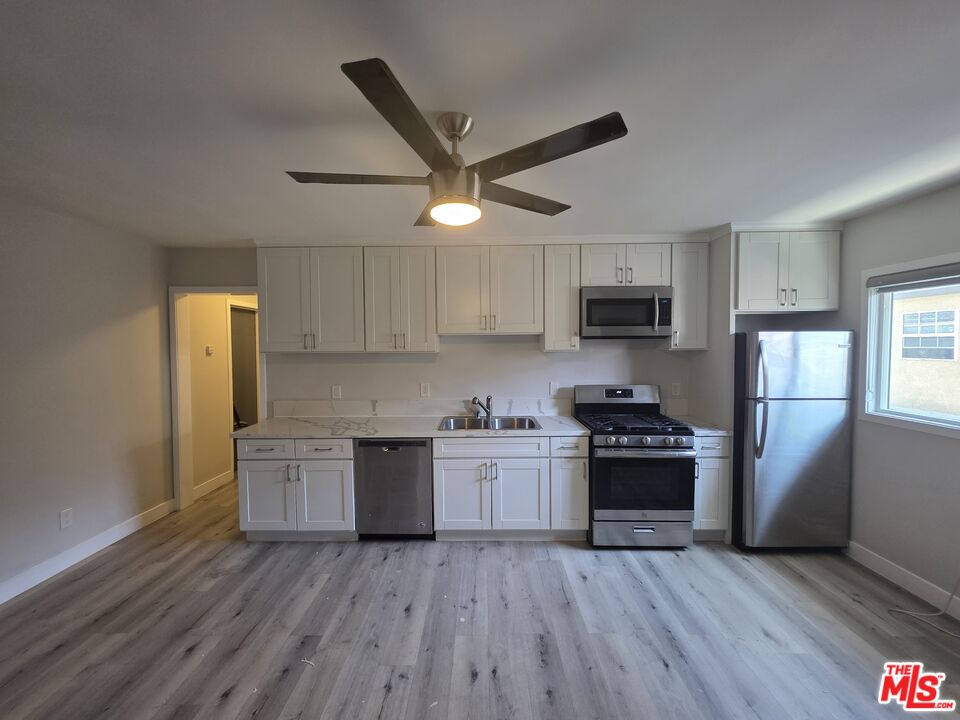 1505 South Cochran Avenue, Unit 4 Los Angeles, CA 90019 - Photo 2 of 45 a kitchen with wooden floors and stainless steel appliances