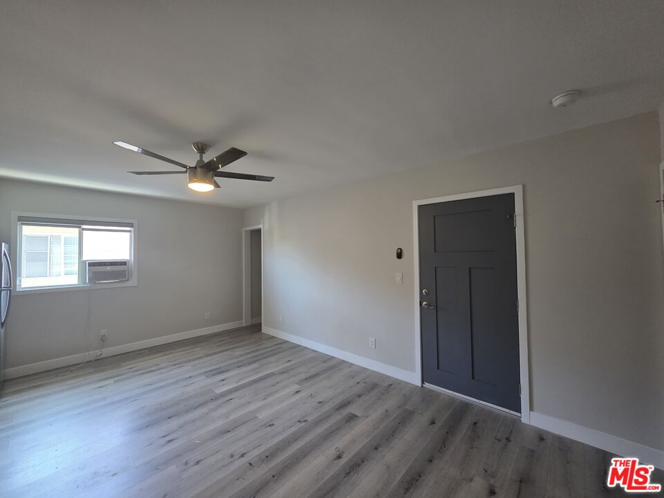 1505 South Cochran Avenue, Unit 4 Los Angeles, CA 90019 - Photo 34 of 45 an empty room with wooden floor fan and windows
