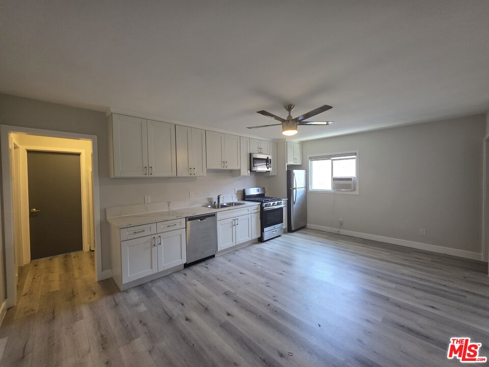 1505 South Cochran Avenue, Unit 4 Los Angeles, CA 90019 - Photo 5 of 45 a kitchen with granite countertop a sink cabinets and wooden floor
