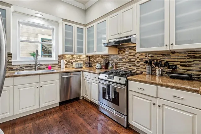 a kitchen with stainless steel appliances granite countertop a sink a stove and cabinets