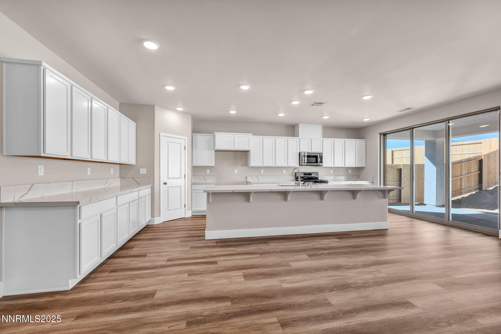 1334 Nebula Road, Unit HOMESITE 94 Carson City, NV 89705 - Photo 2 of 22 a large kitchen with kitchen island a sink wooden floor and a view of living room