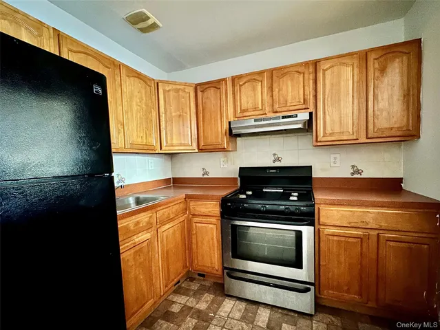 a kitchen with granite countertop a stove top oven cabinetry a sink and a window