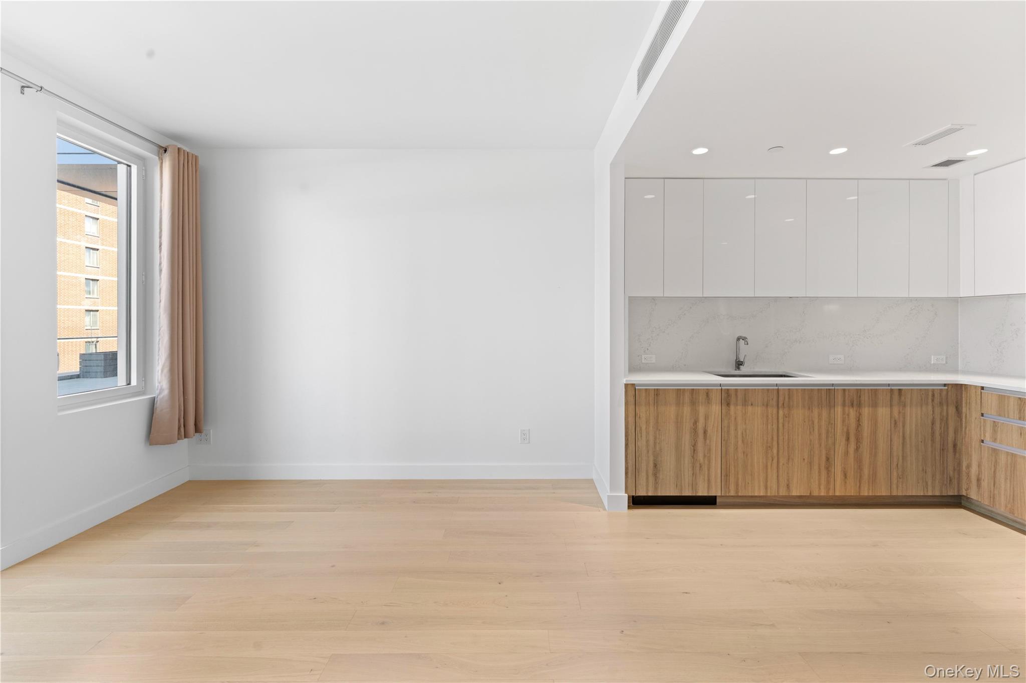 136-18 Maple Avenue, Unit 5G Queens, NY 11355 - Photo 4 of 35 an empty room with wooden floor and windows