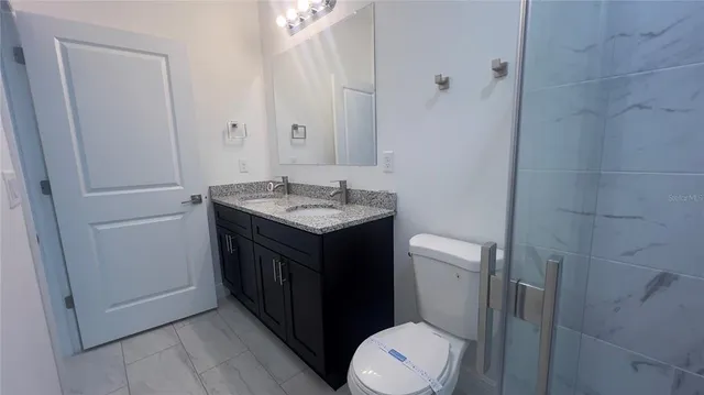 a bathroom with a granite countertop toilet sink and mirror