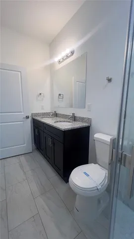 a bathroom with a granite countertop sink a toilet a mirror and shower