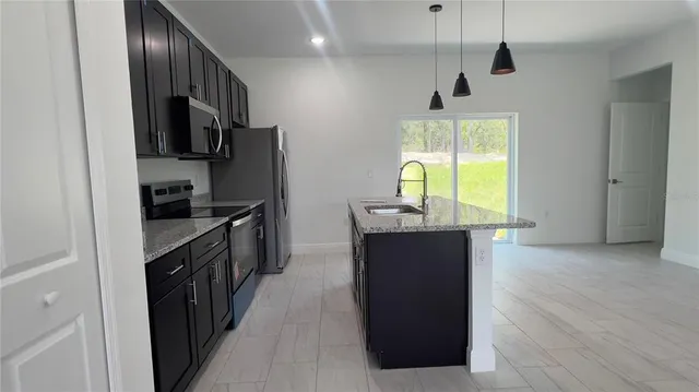 a kitchen with stainless steel appliances granite countertop a refrigerator a sink a stove and a wooden floors