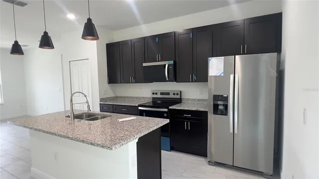 a kitchen with stainless steel appliances granite countertop a refrigerator and a stove top oven