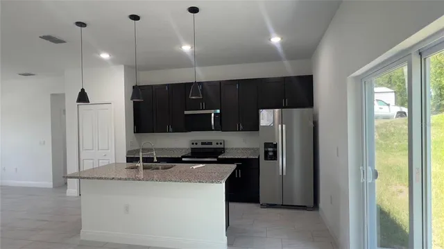 a kitchen with stainless steel appliances granite countertop a refrigerator a sink a stove and a refrigerator with wooden floor