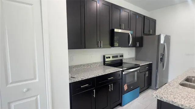 a kitchen with stainless steel appliances granite countertop a stove a refrigerator and a microwave