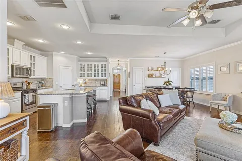 a living room with furniture kitchen view and a wooden floor