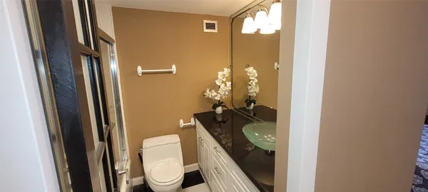 a bathroom with a granite countertop bathtub shower sink vanity and toilet