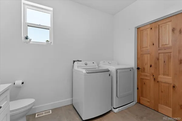 a utility room with a sink a toilet and a window