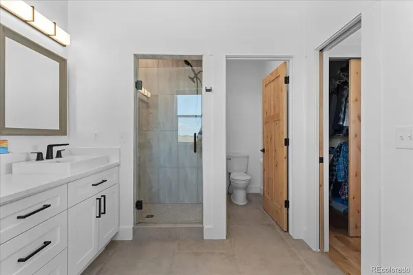 a bathroom with a double vanity sink a toilet and shower