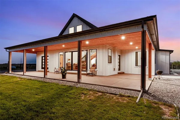 a porch with a table and chairs next to a yard