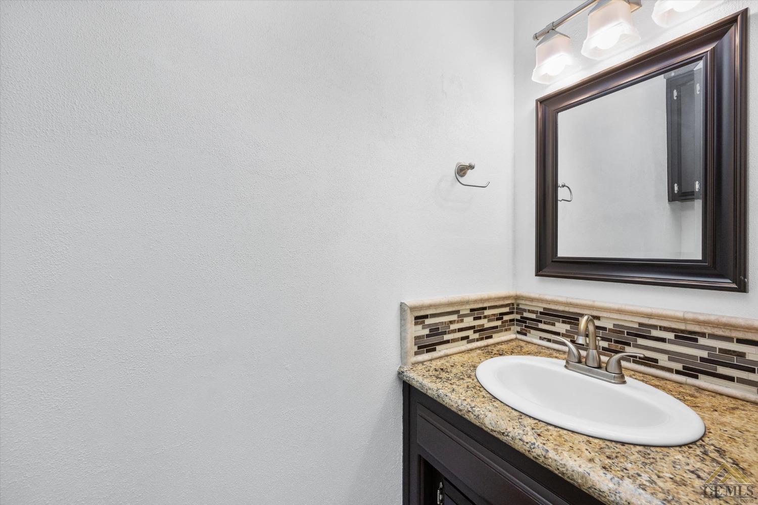 Undisclosed Address Bakersfield, CA 93308 - Photo 26 of 40 a bathroom with a granite countertop sink and a mirror