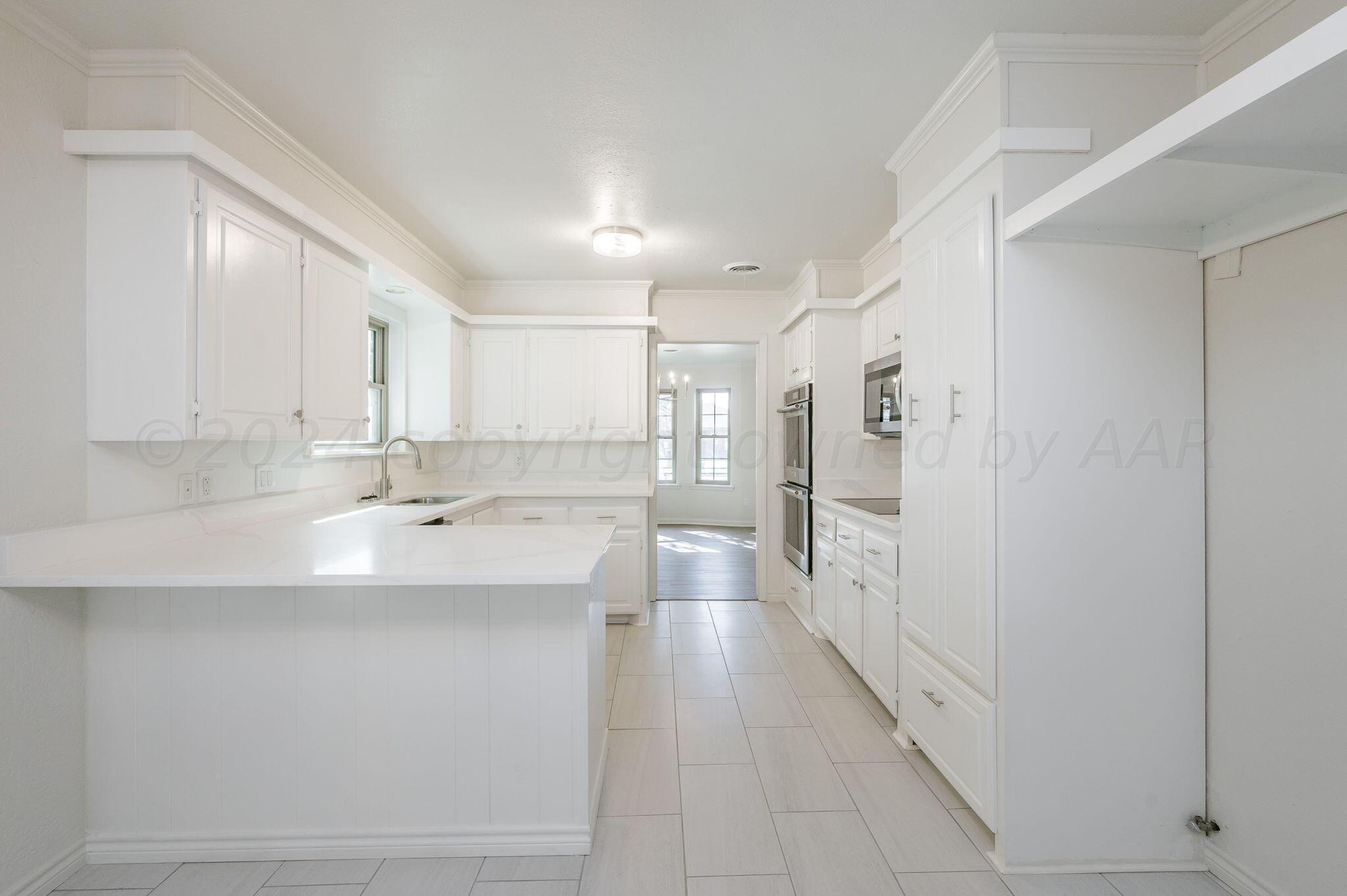 7220 Montague Drive Amarillo, TX 79109 - Photo 6 of 29 a large white kitchen with a sink and dishwasher a refrigerator with white cabinets