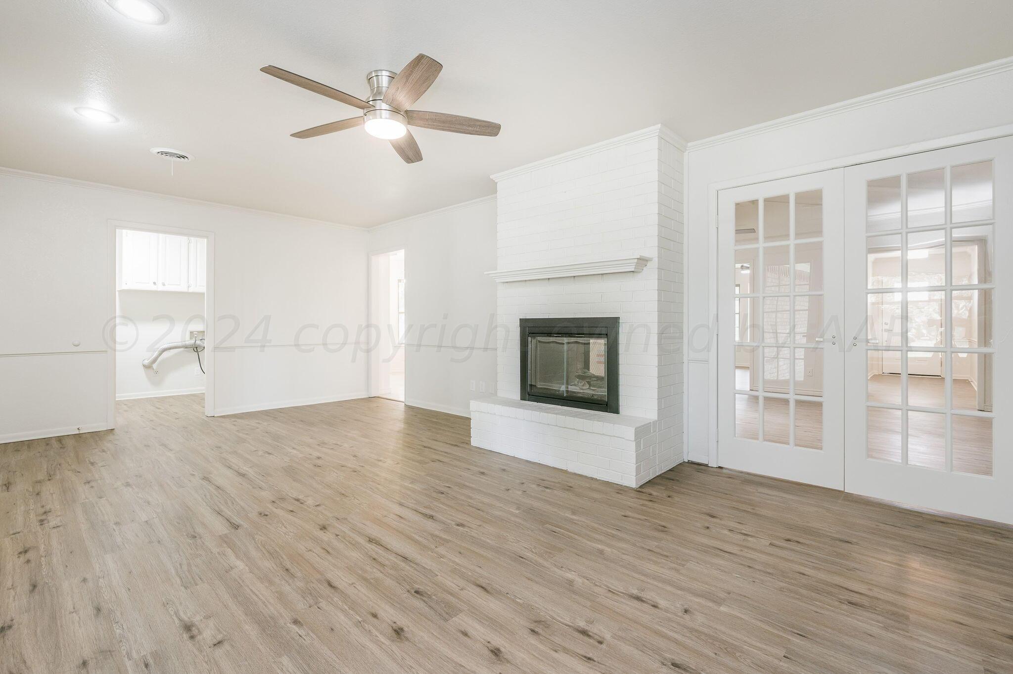 7220 Montague Drive Amarillo, TX 79109 - Photo 10 of 29 an empty room with wooden floor fireplace and windows