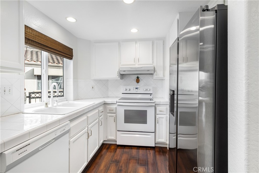430 Lake Street, Unit 304 Huntington Beach, CA 92648 - Photo 21 of 46 a kitchen with kitchen island granite countertop a sink cabinets and stainless steel appliances