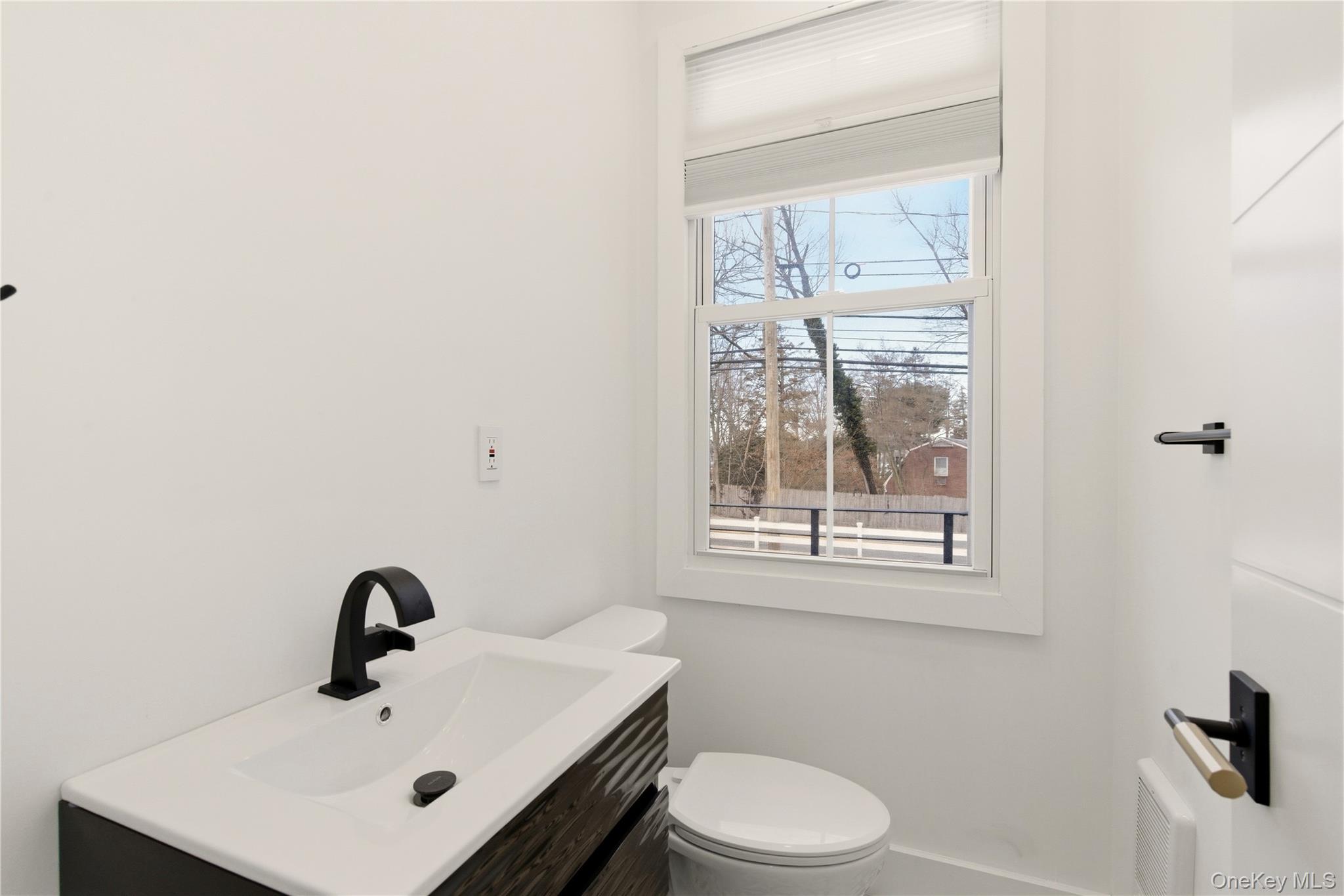 77 Cove Road Oyster Bay, NY 11771 - Photo 15 of 45 a bathroom with a sink a toilet and a window