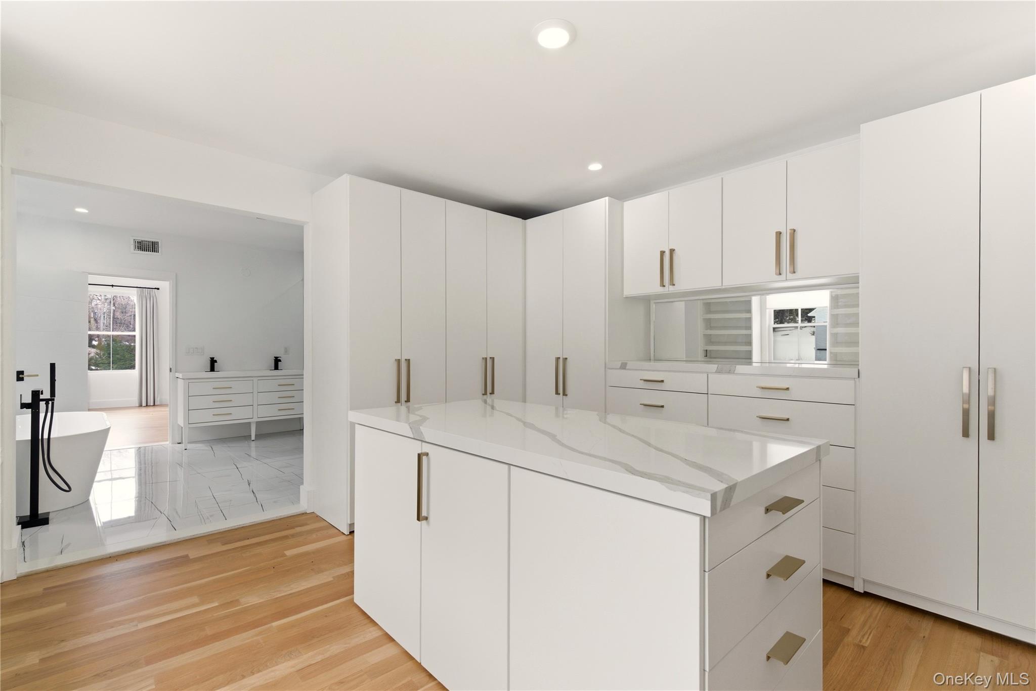 77 Cove Road Oyster Bay, NY 11771 - Photo 22 of 45 a view of a kitchen with kitchen island a sink a stove a refrigerator and white cabinets