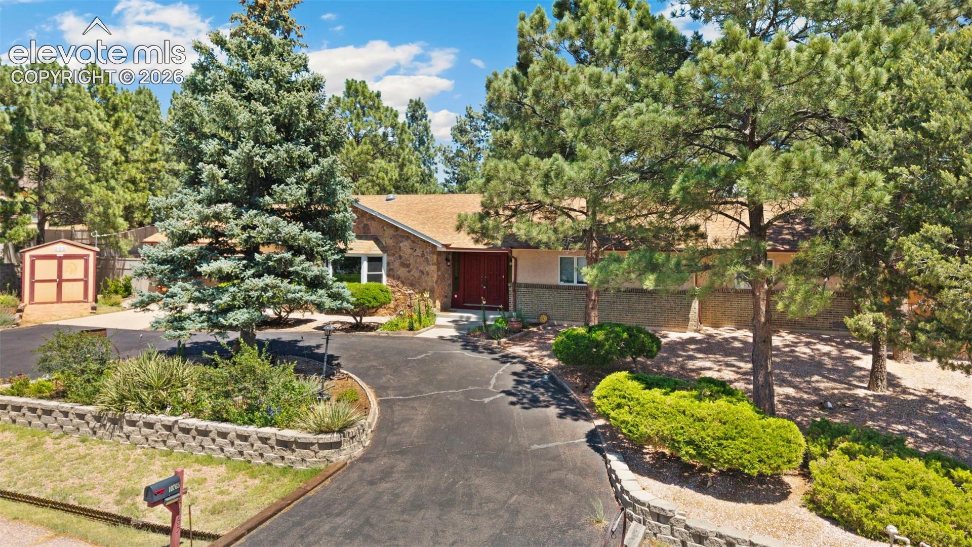10765 Falling Star Road Fountain, CO 80817 - Photo 27 of 27 Ranch-style exterior with a stone facade, a red entry door, and a brown shingle roof