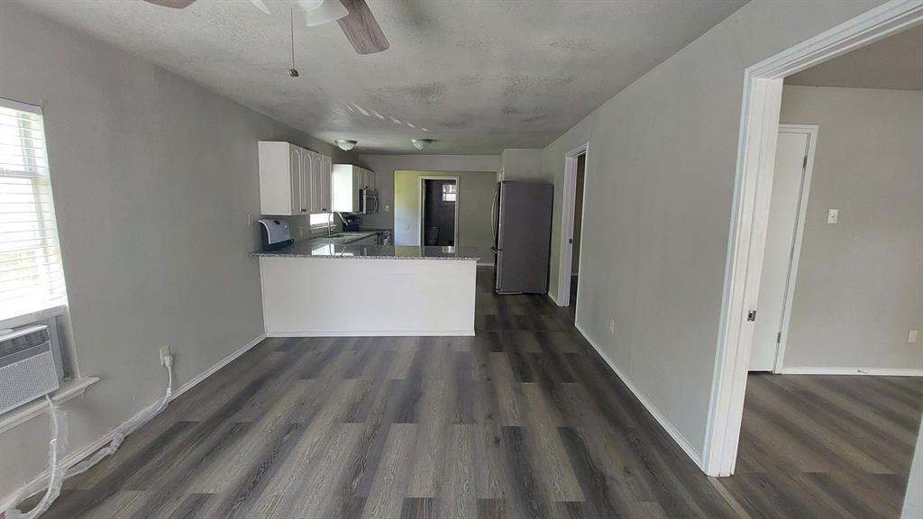 1107 Beech Street Bonham, TX 75418 - Photo 11 of 14 a view of a hallway with wooden floor and a kitchen space