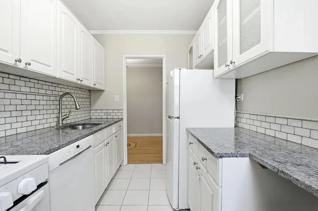 a kitchen with granite countertop a sink stove and refrigerator