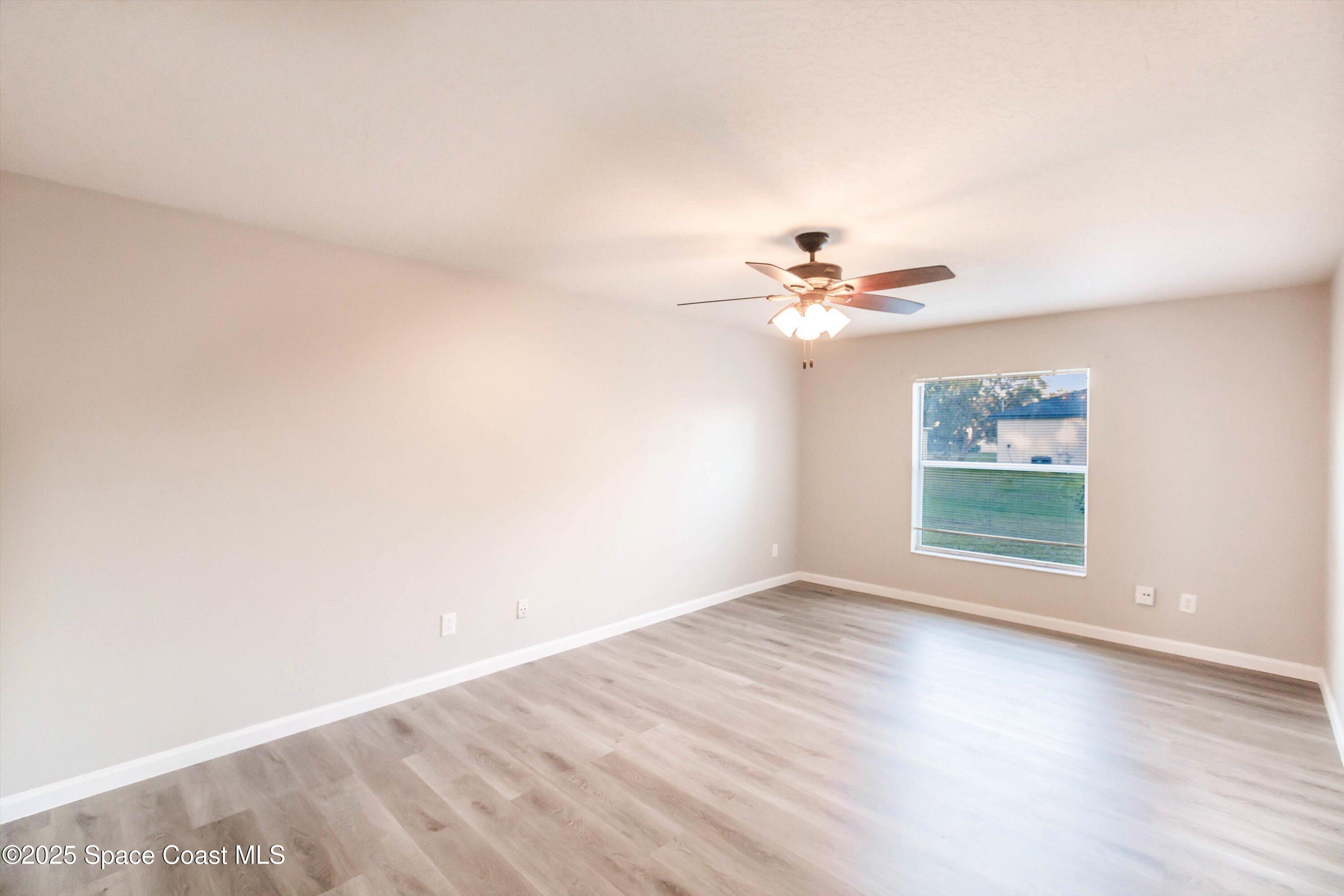 3061 Tazewell Avenue Southeast Palm Bay, FL 32909 - Photo 16 of 30 a view of a room with wooden floor and a ceiling fan