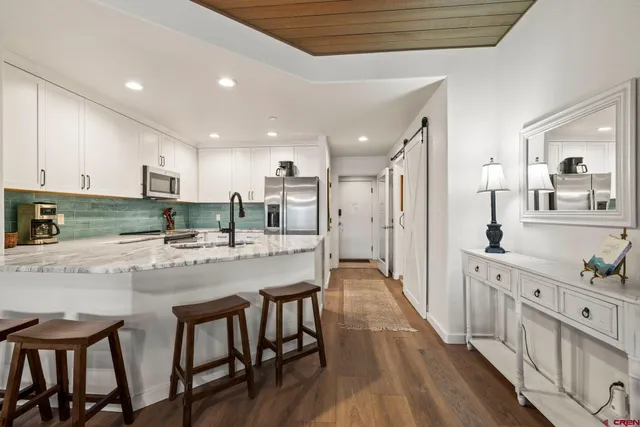 a kitchen with stainless steel appliances granite countertop a table chairs sink refrigerator and cabinets