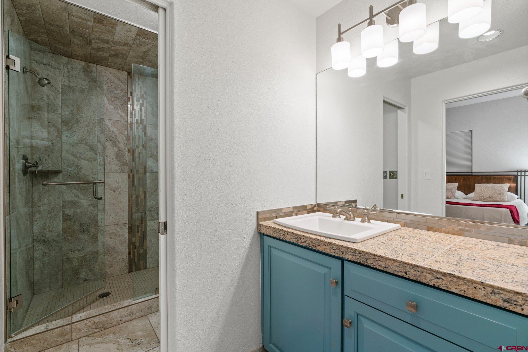 117 Needles Way, Unit 624 Durango, CO 81301 - Photo 9 of 32 a bathroom with a granite countertop sink a mirror and a shower