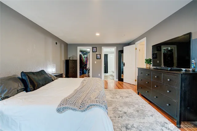 a bedroom with a large bed and a flat tv screen on dresser