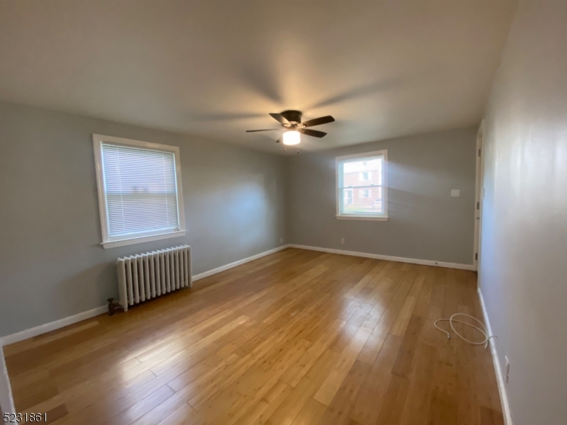 24 East 7th Street, Unit 2 Clifton, NJ 07011 - Photo 1 of 5 a view of an empty room with wooden floor and a window