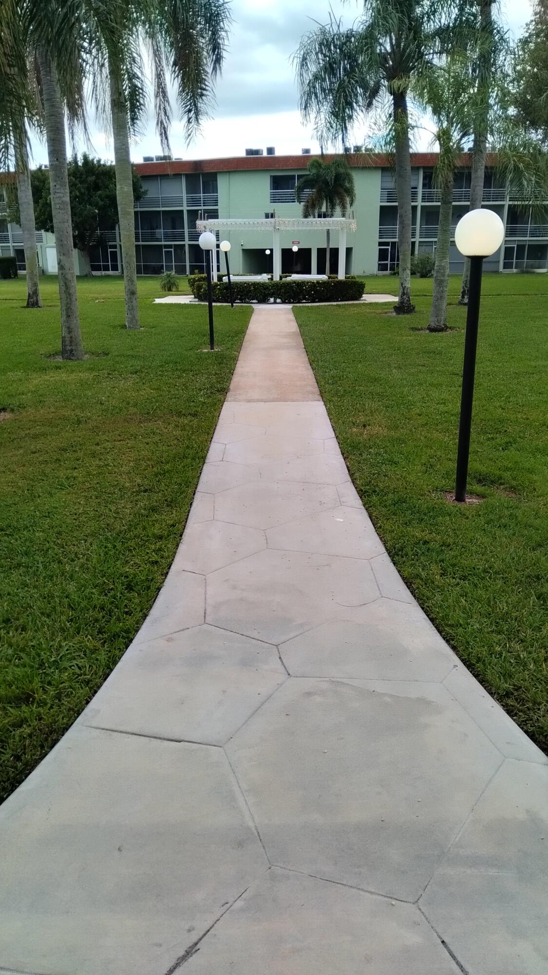 3300 Springdale Boulevard, Unit 208 Palm Springs, FL 33461 - Photo 19 of 21 a view of a white house with a yard and palm trees