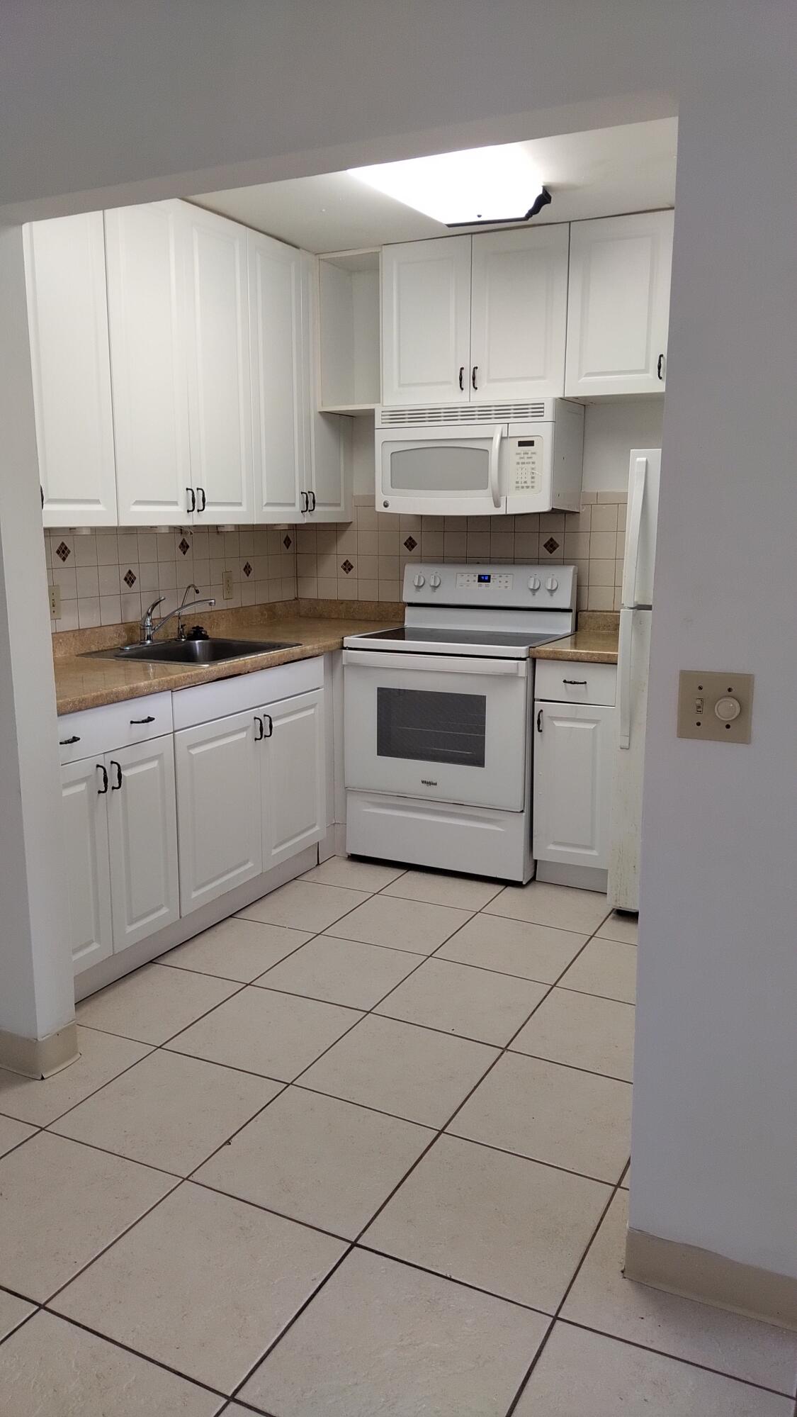 3300 Springdale Boulevard, Unit 208 Palm Springs, FL 33461 - Photo 10 of 21 a kitchen with a stove sink and cabinets