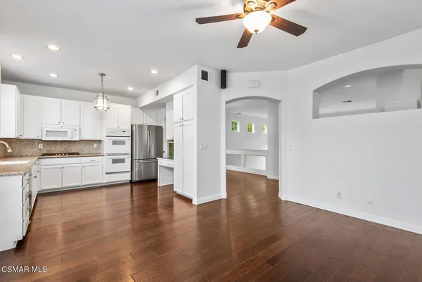 a view of a kitchen with a refrigerator a ceiling fan and wooden floor