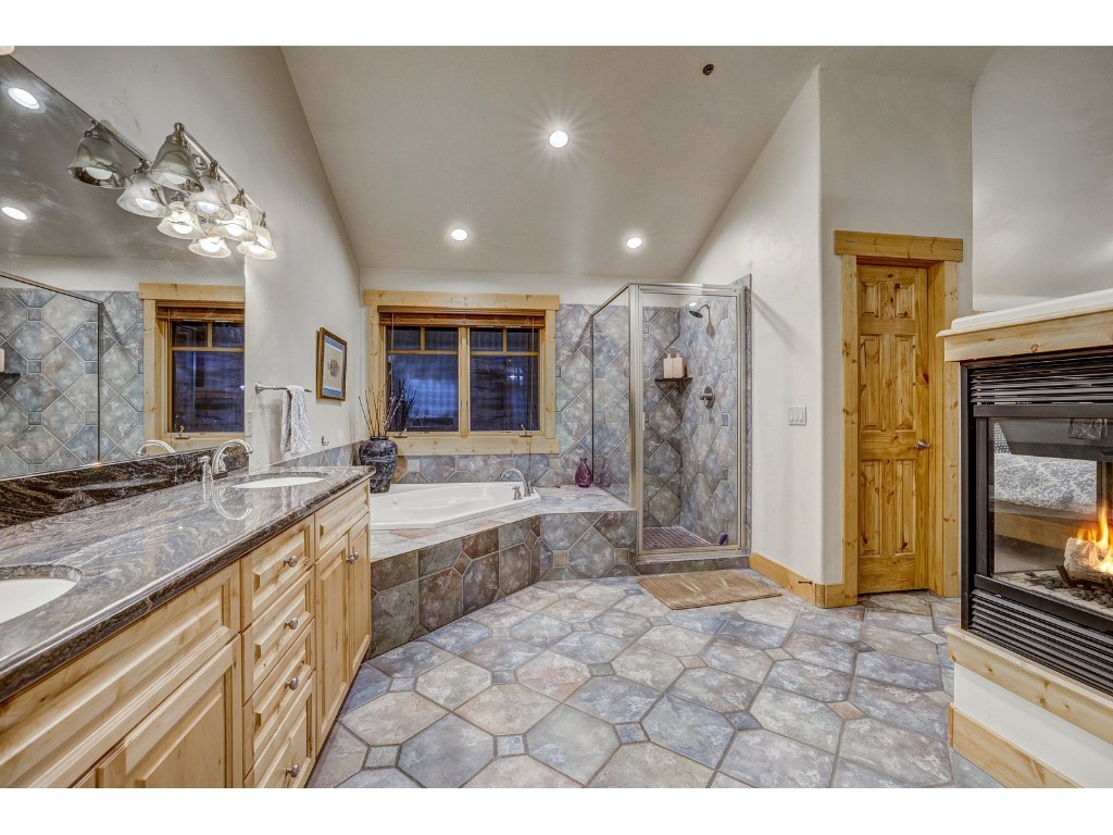 397 Whispering Pines Circle Blue River, CO 80424 - Photo 20 of 35 a bathroom with a granite countertop sink a large mirror and a bathtub