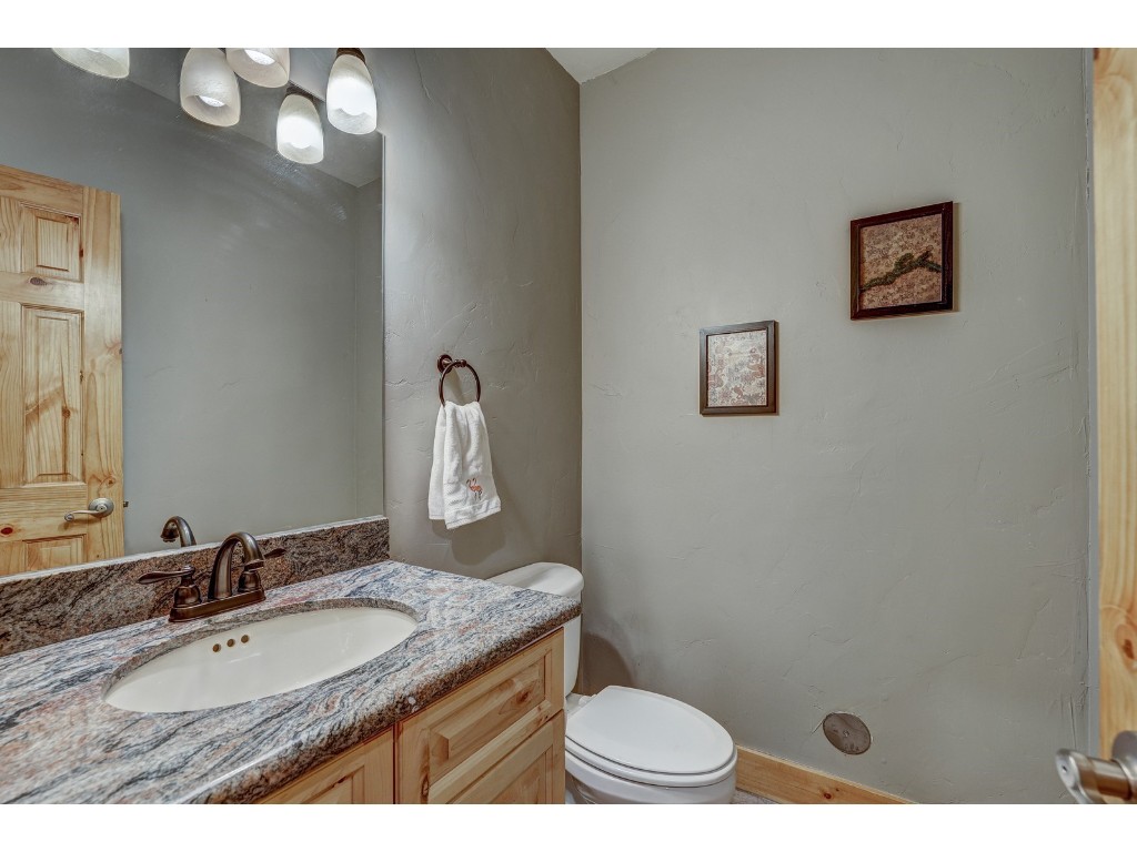 397 Whispering Pines Circle Blue River, CO 80424 - Photo 24 of 35 a bathroom with a granite countertop sink a toilet a mirror and shower