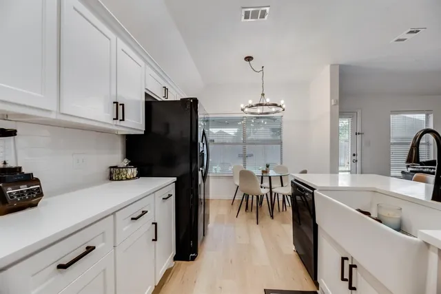 a kitchen with a sink a refrigerator and chairs