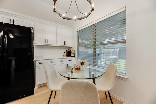 a kitchen with stainless steel appliances granite countertop a dining table chairs and a refrigerator