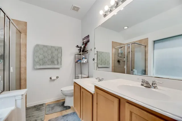 a bathroom with a double vanity sink toilet and a mirror