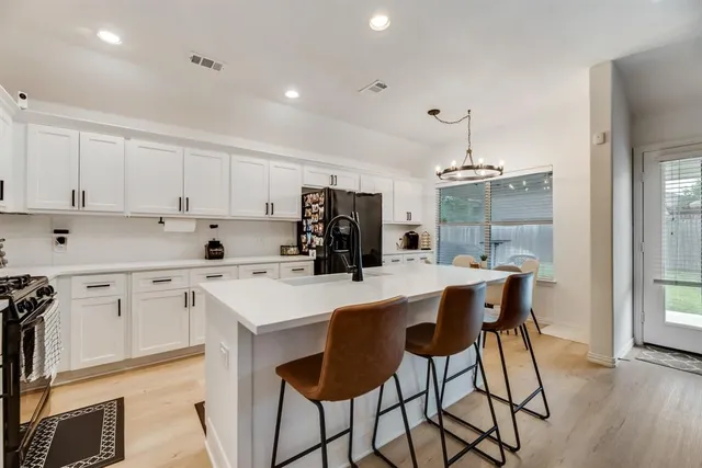 a kitchen with a table a refrigerator a cabinets and stools