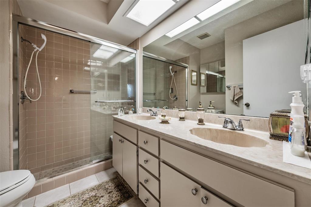 9302 Trowbridge Court New Port Richey, FL 34655 - Photo 24 of 41 a bathroom with a double vanity sink toilet mirror and shower